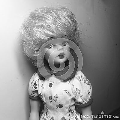 An adorable vintage doll is standing lean against to the wall in gray scale Editorial Stock Photo